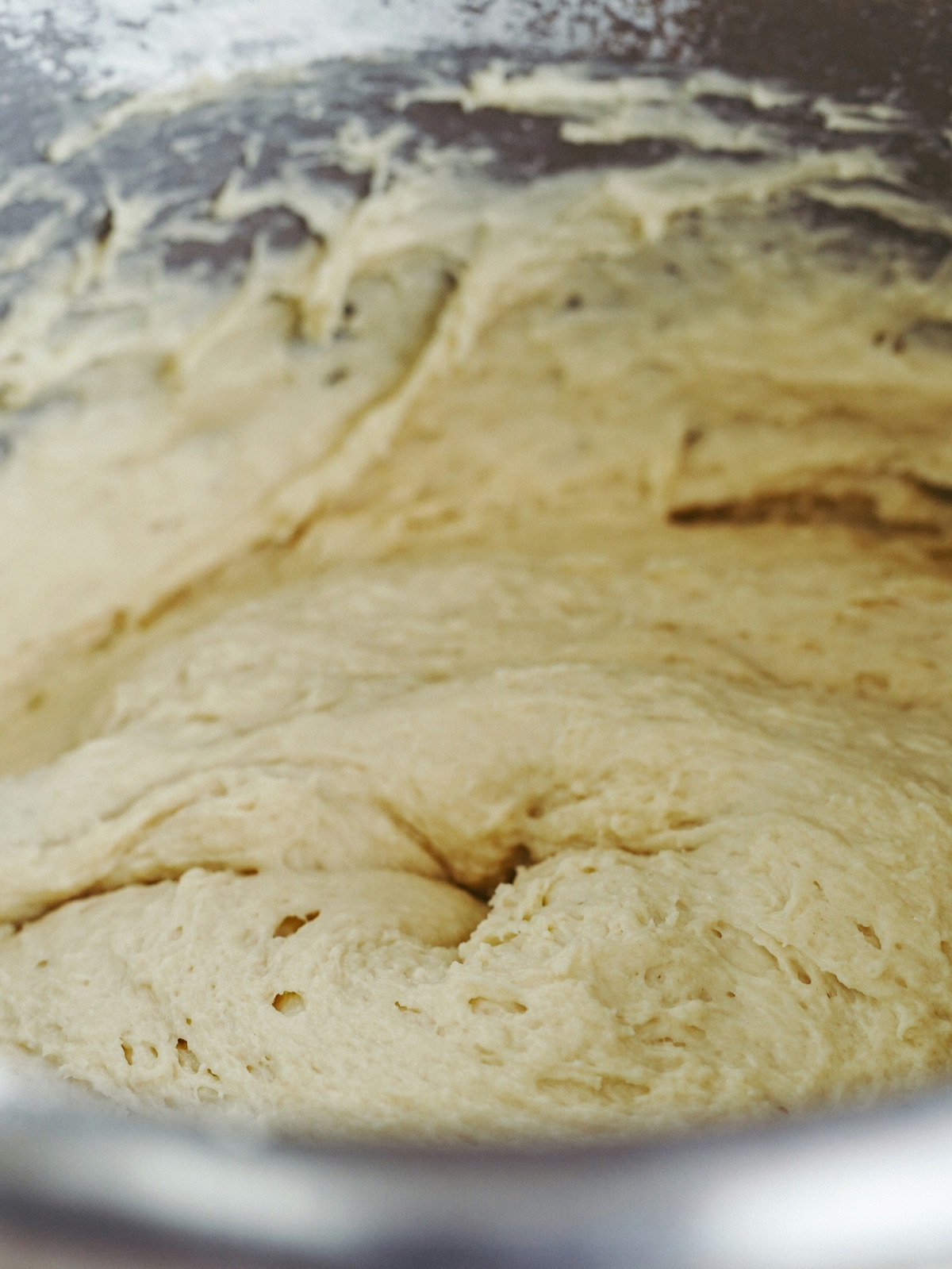 Enriched dough smeared against the side of a mixing bowl during early mixing