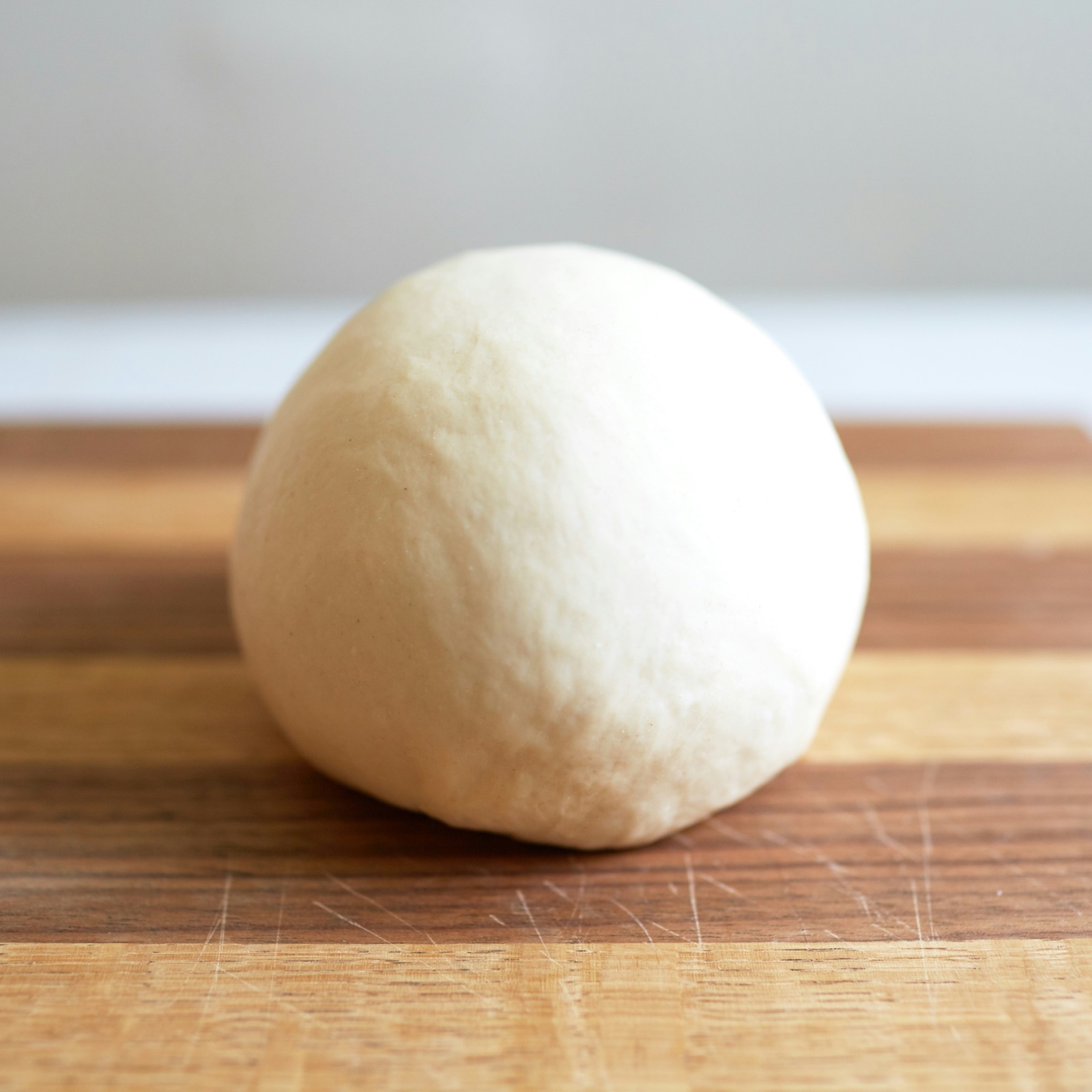Smooth ball of lean dough on a wooden board